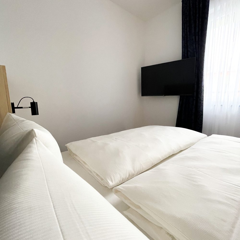 Blick auf den Fernseher aus dem Bett im Apartment Familienzimmer im Holi City Apart Hotel Berlin